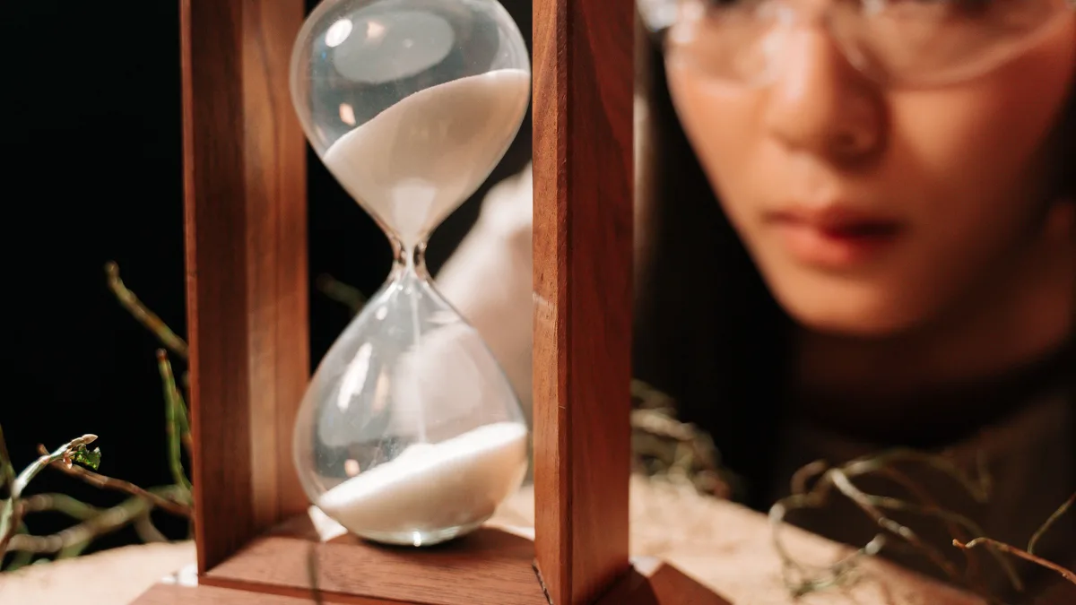 An hourglass with coins — time and compounding decide how soon each FIRE path lets you step back from work