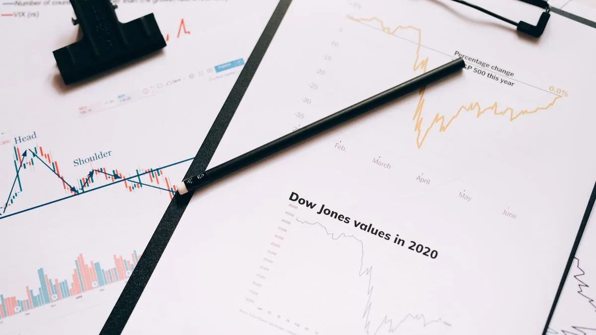 How to calculate intrinsic value, step by step A pen lies across printed stock charts on a clipboard, including a page titled Dow Jones values in 2020.