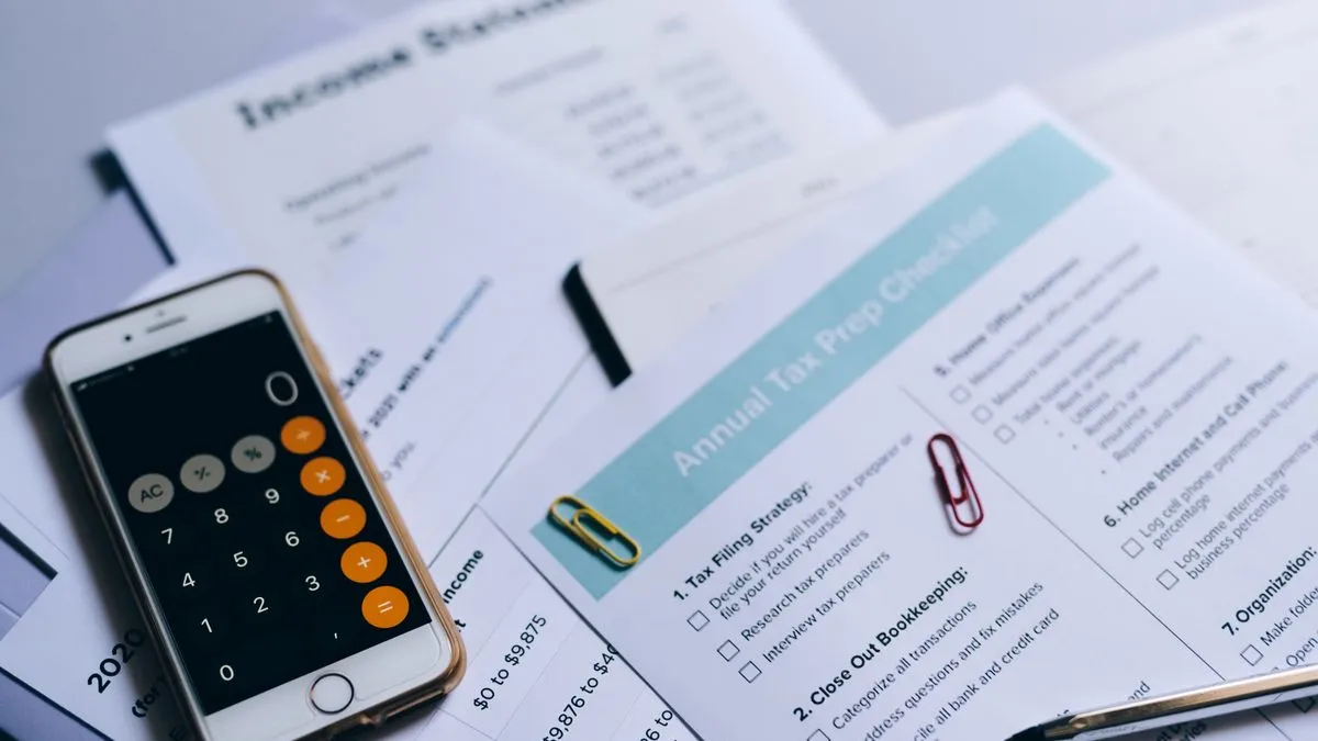 Vorabpauschale: Germany's Advance ETF Tax Explained A smartphone calculator rests on spread-out tax paperwork, including an annual tax preparation checklist and income statements.